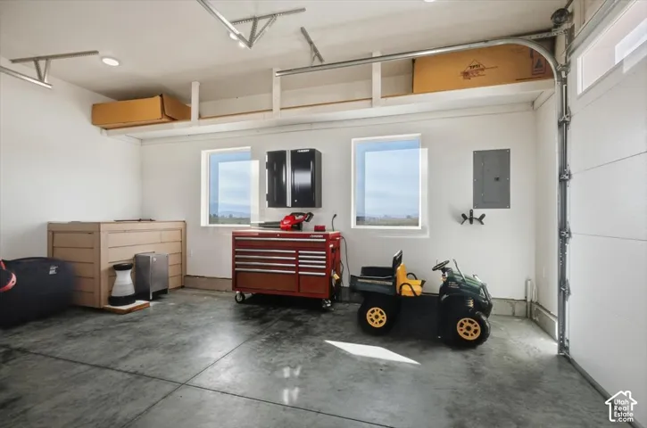 Spacious garage featuring a concrete floor, built-in overhead shelving, recessed ceiling lighting, and two windows