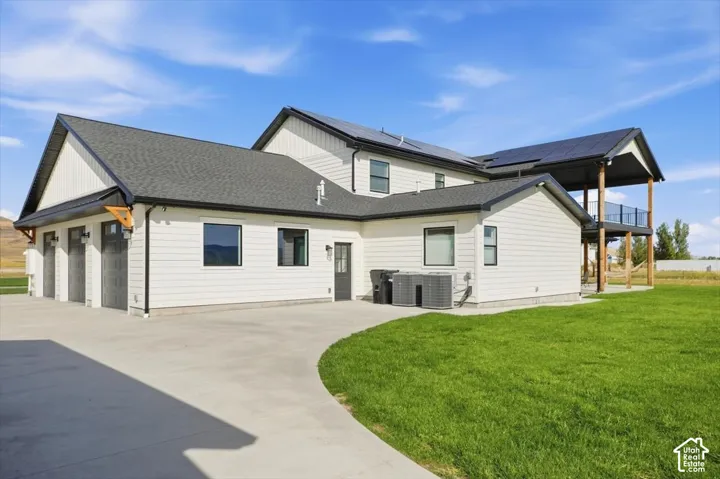 Contemporary exterior with white siding, dark trim, a three-car garage, and a covered upper-level deck with glass railings