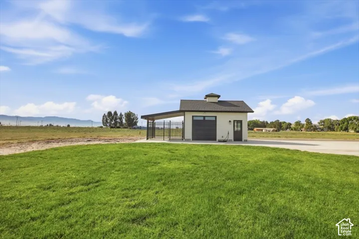 Detached structure featuring a dark garage door, cupola, and covered side area with fencing