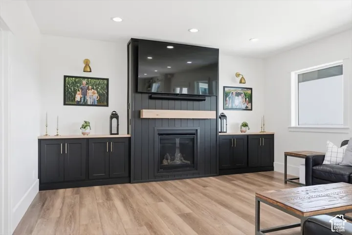Built-in fireplace with a light wood mantle, flanked by custom black cabinetry with natural wood countertops and modern gold sconces