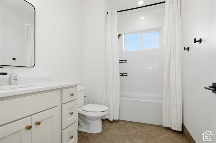 White vanity with gold-tone hardware, rectangular mirror, and wood-finish flooring