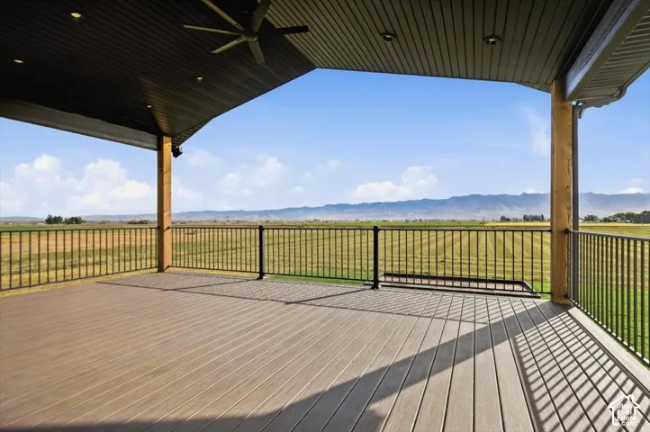 Expansive covered deck featuring wood-finish decking, black metal railing, a ceiling fan, and recessed lighting