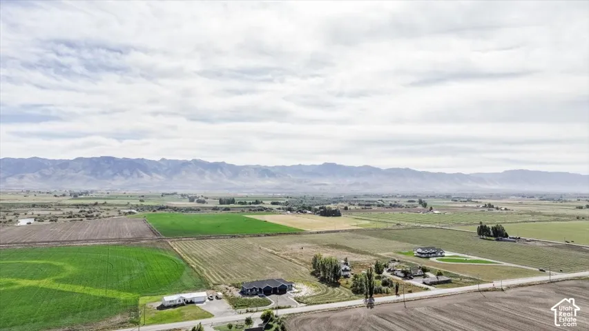 Expansive rural landscape with distant mountain ranges, agricultural fields, and scattered residential properties