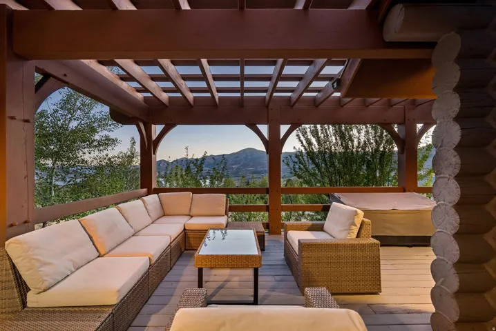 Expansive outdoor deck with a pergola, wood-finish flooring, and a railing overlooking a natural landscape