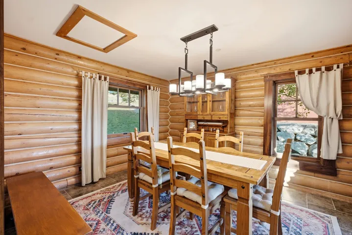 Log-clad walls, recessed ceiling light, and a modern linear chandelier