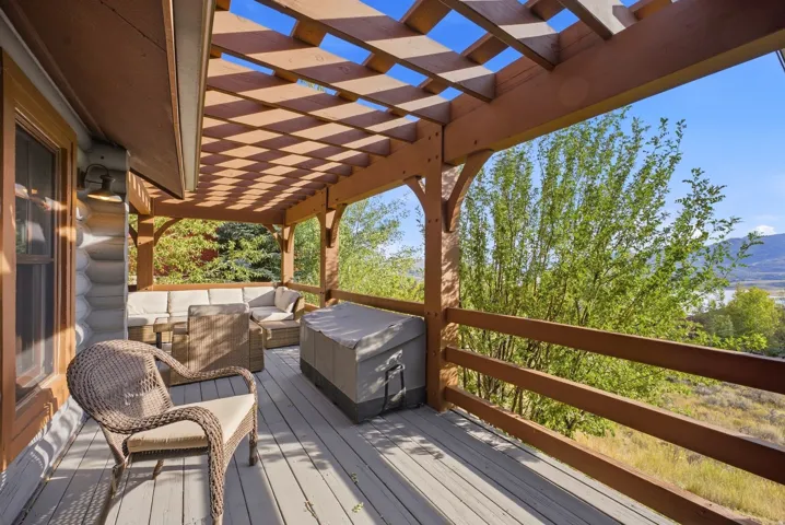 Expansive wood deck with a slatted pergola, log-style exterior, and wood railing