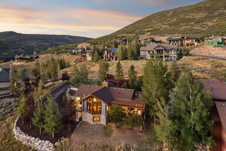 Expansive hillside property featuring a multi-level residence with stone and timber accents, a covered outdoor living area, and a stone retaining wall