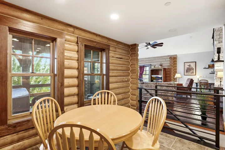 Log wall paneling, tile flooring, wood-framed windows, recessed lighting, and metal railing