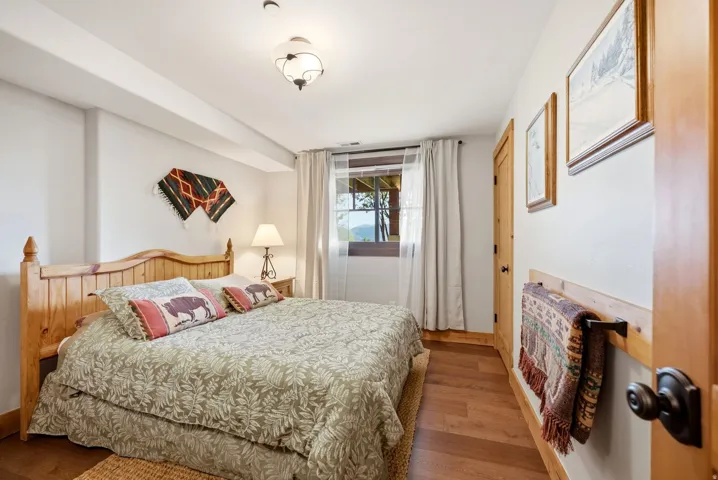 Wood-finish flooring, wood framed window, wood paneled bed frame, and a bronze light fixture
