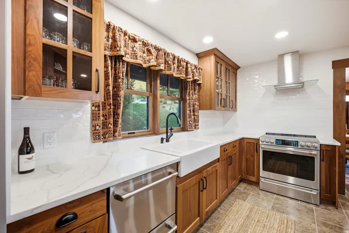 Kitchen featuring wood cabinetry, white countertops, stainless steel appliances, a farmhouse sink, and recessed lighting