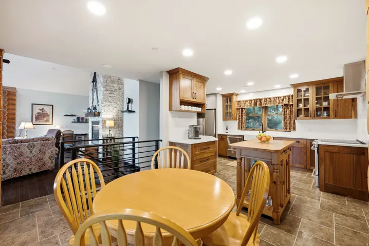 Kitchen featuring extensive wood cabinetry, stainless steel appliances, a wood-finish island, and tile flooring