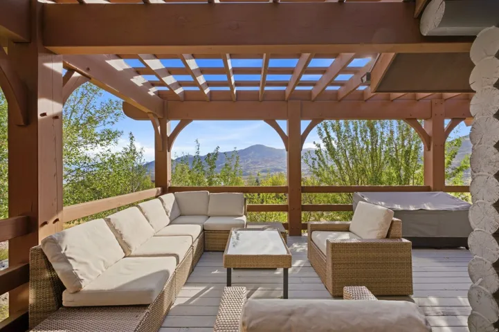 Expansive outdoor deck featuring a wooden pergola, protective railing, and a hot tub