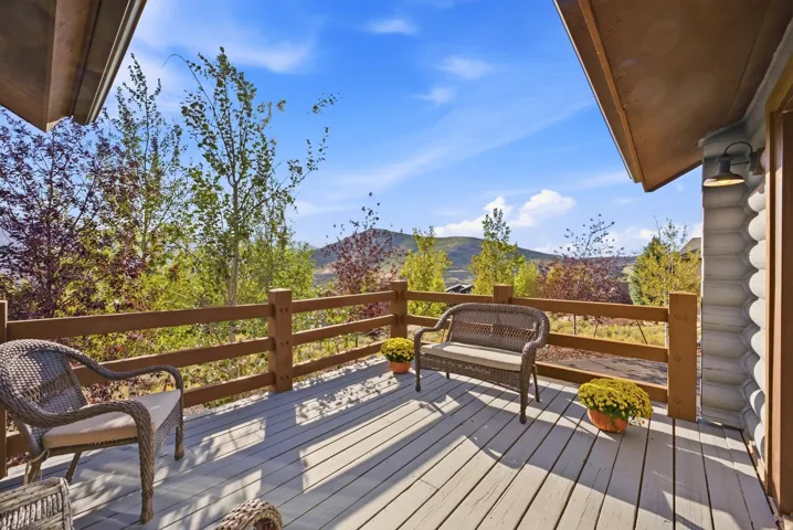 Expansive outdoor deck with wood-finish railing, featuring log-style siding and an exterior wall lantern
