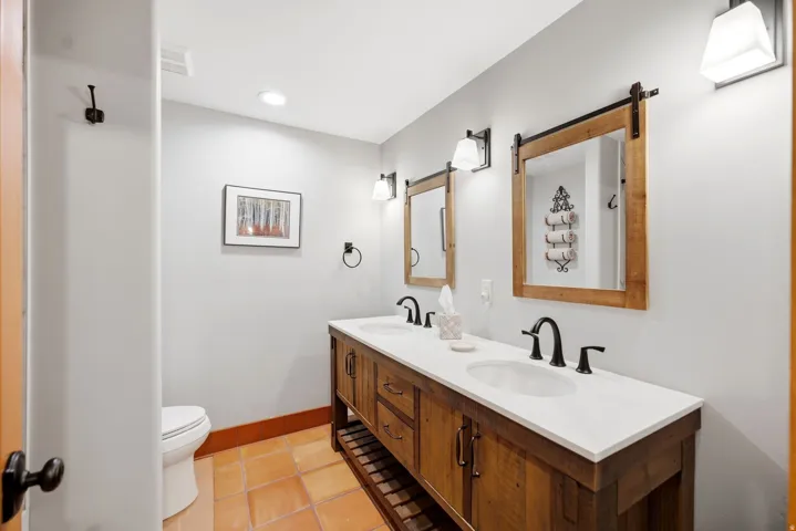 Dual vanity with wood-finish cabinetry, white countertop, and integrated sinks