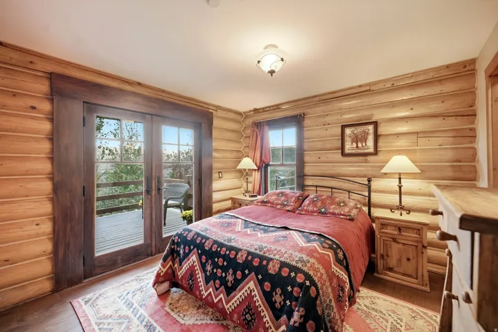 Wood-finish wall paneling, wood-finish flooring, glass-paned double doors, wood-frame window, and a ceiling-mounted light fixture