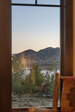 Window framing a mountain backdrop, a body of water, and natural landscaping
