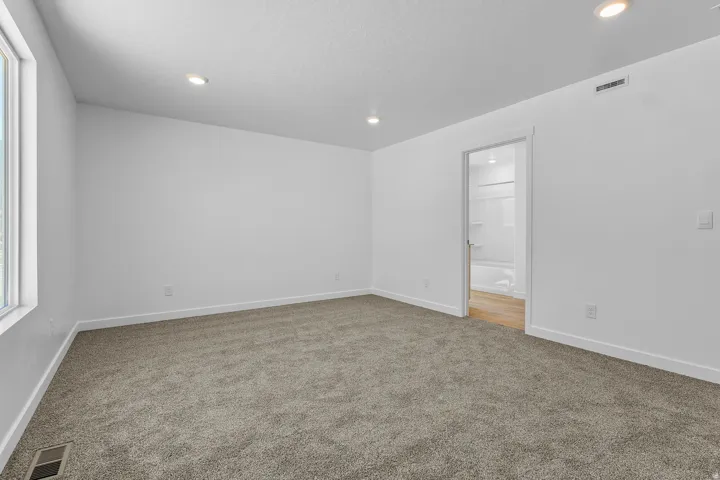 Plush carpet flooring, recessed lighting, and bright white walls