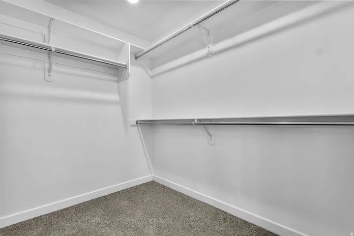 Built-in shelving with integrated hanging rods, recessed ceiling lighting, and carpet flooring