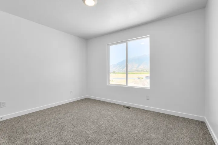Recessed ceiling light fixture, white walls, gray carpet flooring, and a large window