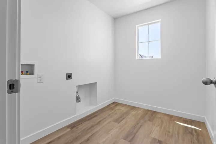 Bright utility space featuring wood-finish flooring, a window, and white walls