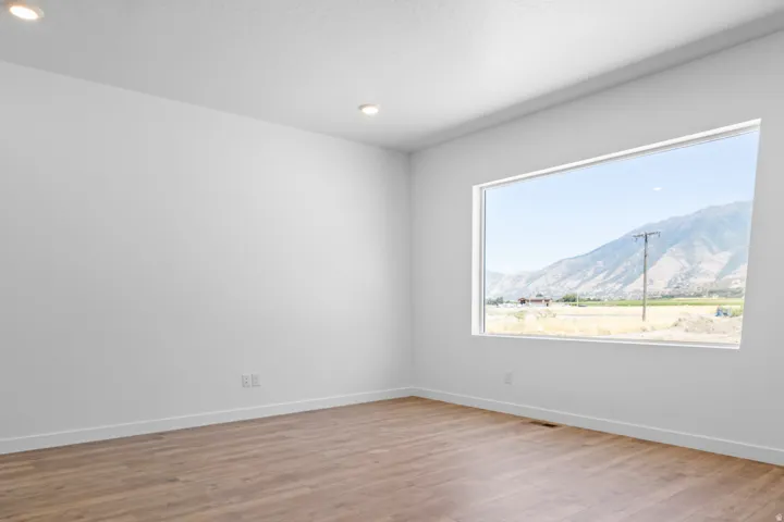 Expansive horizontal window, wood-finish flooring, recessed ceiling lighting, and crisp white walls
