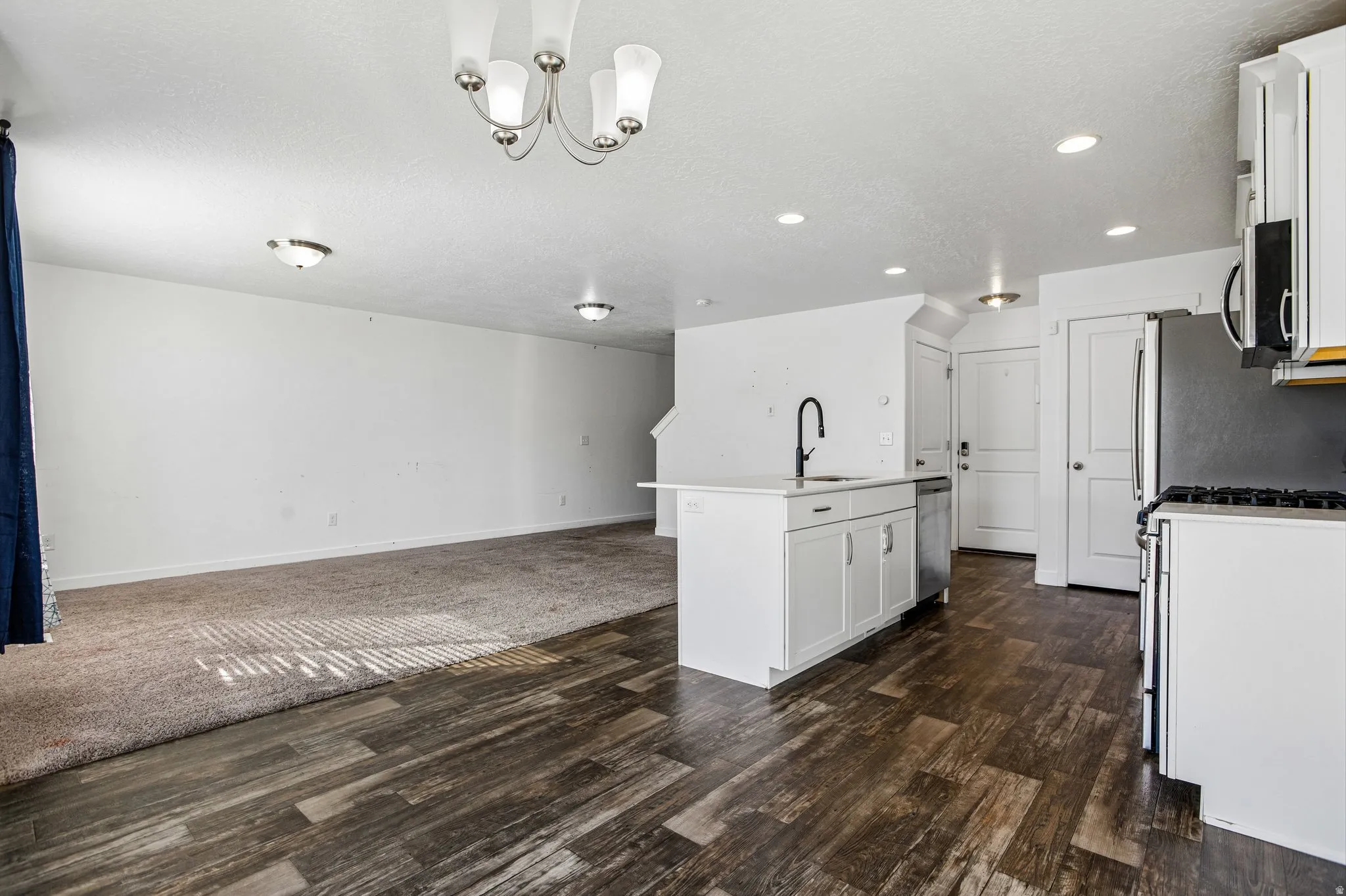 Kitchen island with white cabinetry and an undermount sink, wood-finish flooring, and recessed lighting