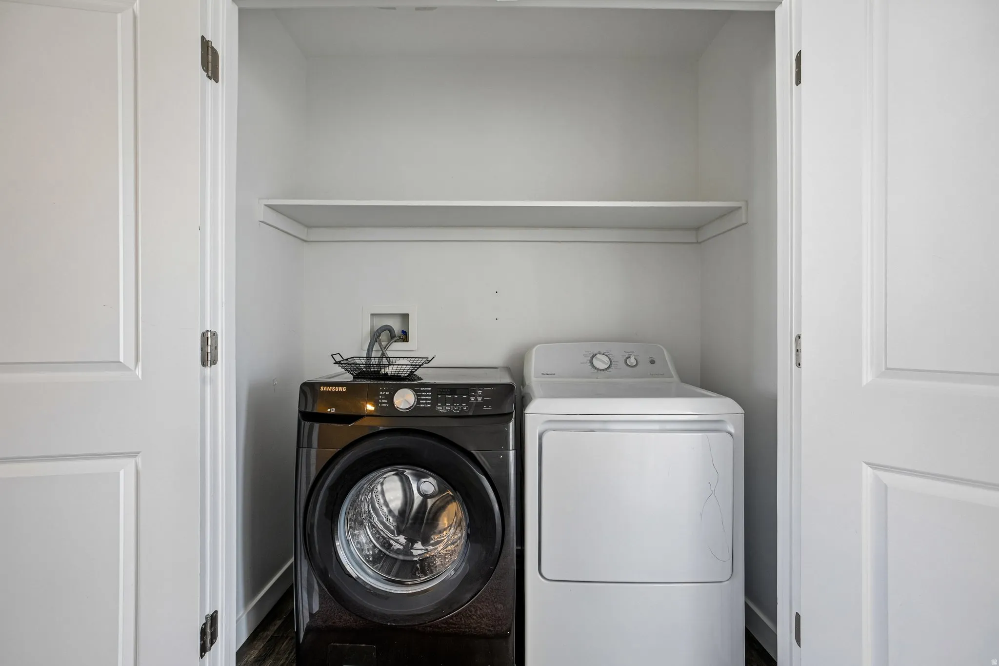 Built-in laundry closet with a single storage shelf and double panel doors