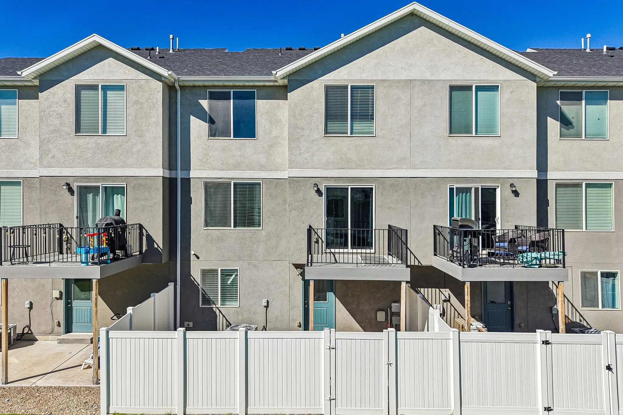 Stucco exterior with multiple balconies featuring black metal railings