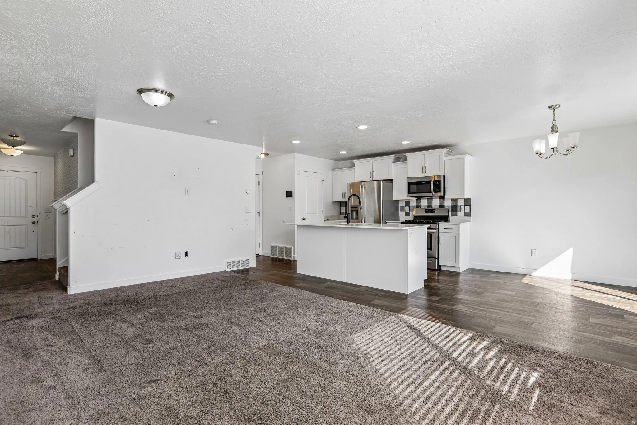 Contemporary kitchen featuring white cabinetry, a large center island, stainless steel appliances, and a tiled backsplash
