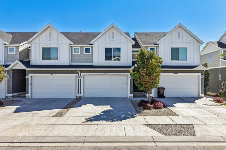 Modern townhome exterior with board and batten accents, attached two-car garage, and concrete driveway