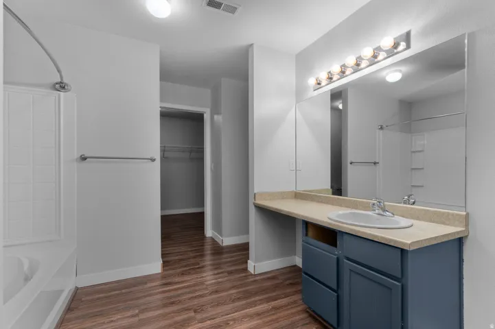 Bathroom featuring a vanity with an integrated sink, broad mirror, and a shower-tub combination