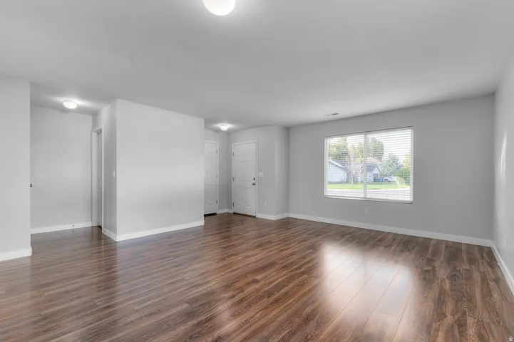 Expansive living area featuring wood-finish flooring, recessed lighting, and a large window with blinds