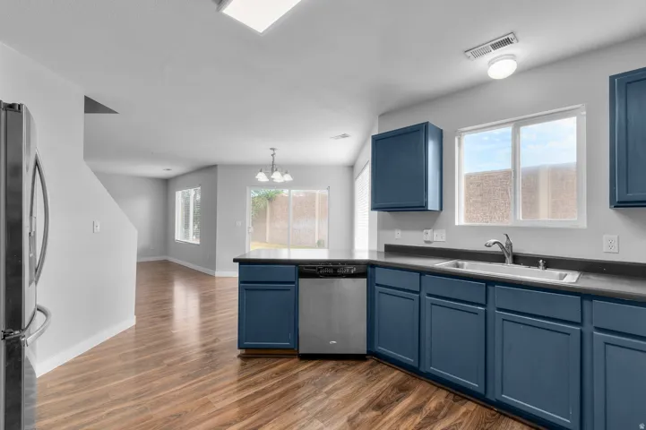 Kitchen featuring blue cabinetry, dark countertops, a stainless steel dishwasher, and a single-basin sink