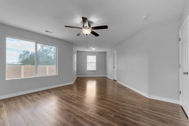 Spacious interior with wood-finish flooring, light gray wall tones, and multiple windows