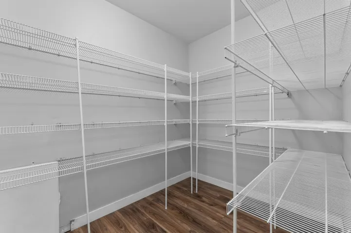 Walk-in closet featuring extensive wire shelving, wood-finish flooring, and light-toned walls
