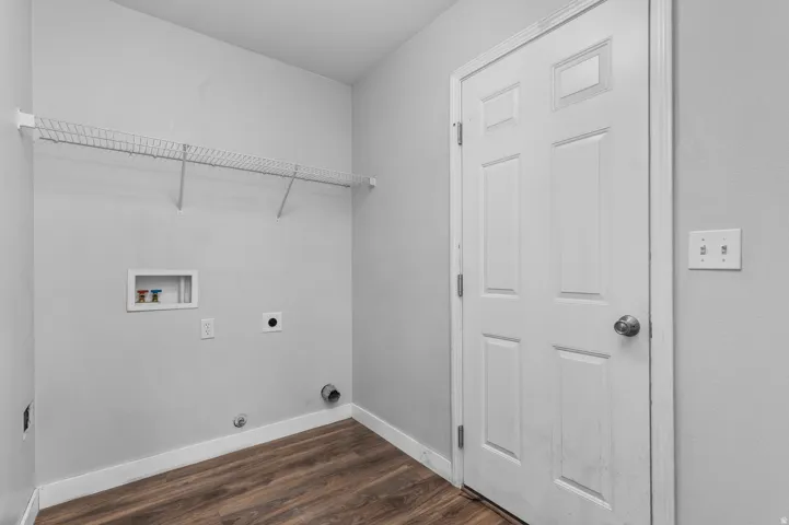 Laundry area with durable wood-finish flooring, light grey wall paint, and a white wire shelf