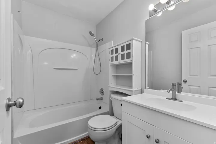 Vanity with integrated sink, brushed nickel faucet, wall-mounted mirror, and overhead vanity lighting