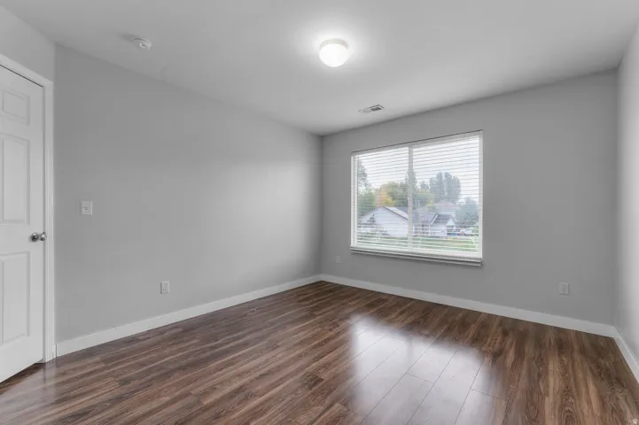 Wood-finish flooring, white trim, and a window with horizontal blinds