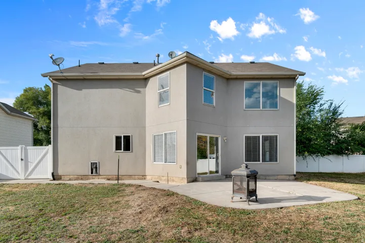 Stucco exterior with multiple windows, a sliding glass door, and a concrete patio