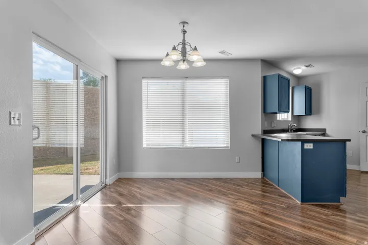 Wood-finish flooring, sliding glass door, pendant lighting, recessed lighting, and kitchen island with built-in sink