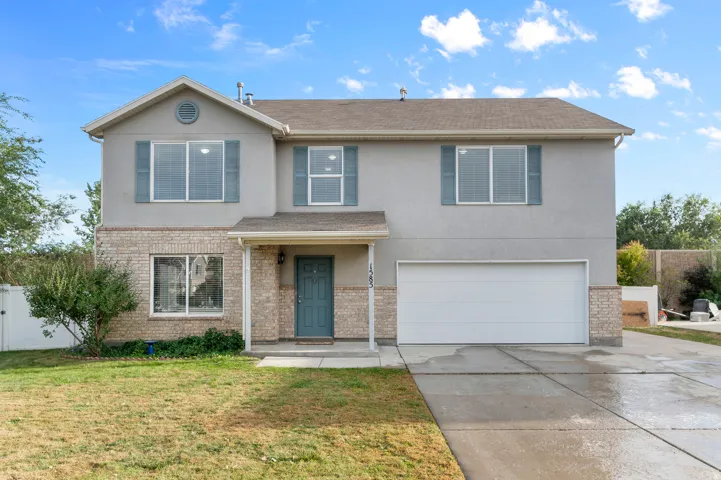 Two-story residence featuring a two-car garage, stone and stucco exterior, and a covered entryway