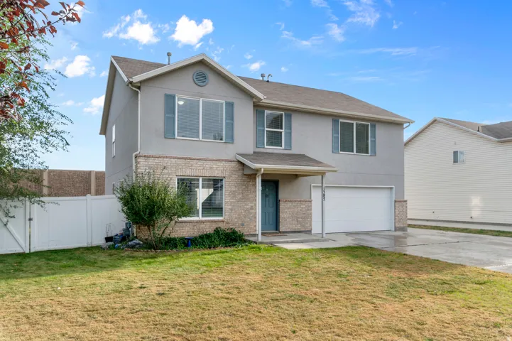 Contemporary two-story exterior featuring a brick and stucco facade, an attached garage, and a covered entryway