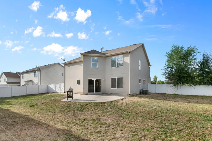 Rear exterior with concrete patio, sliding glass doors, and a partial privacy fence