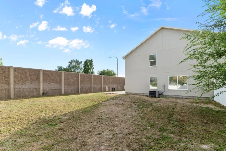 Expansive yard featuring a concrete privacy wall and a two-story exterior with multiple windows