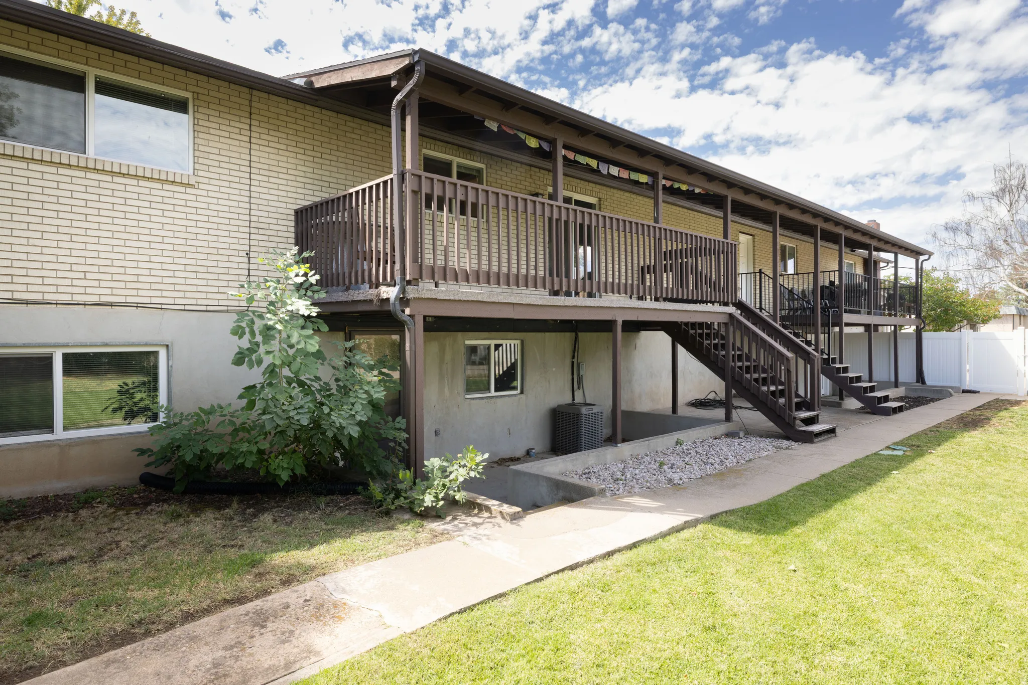Expansive upper-level deck with dark wood railing and two sets of stairs, offering direct access to the lower level