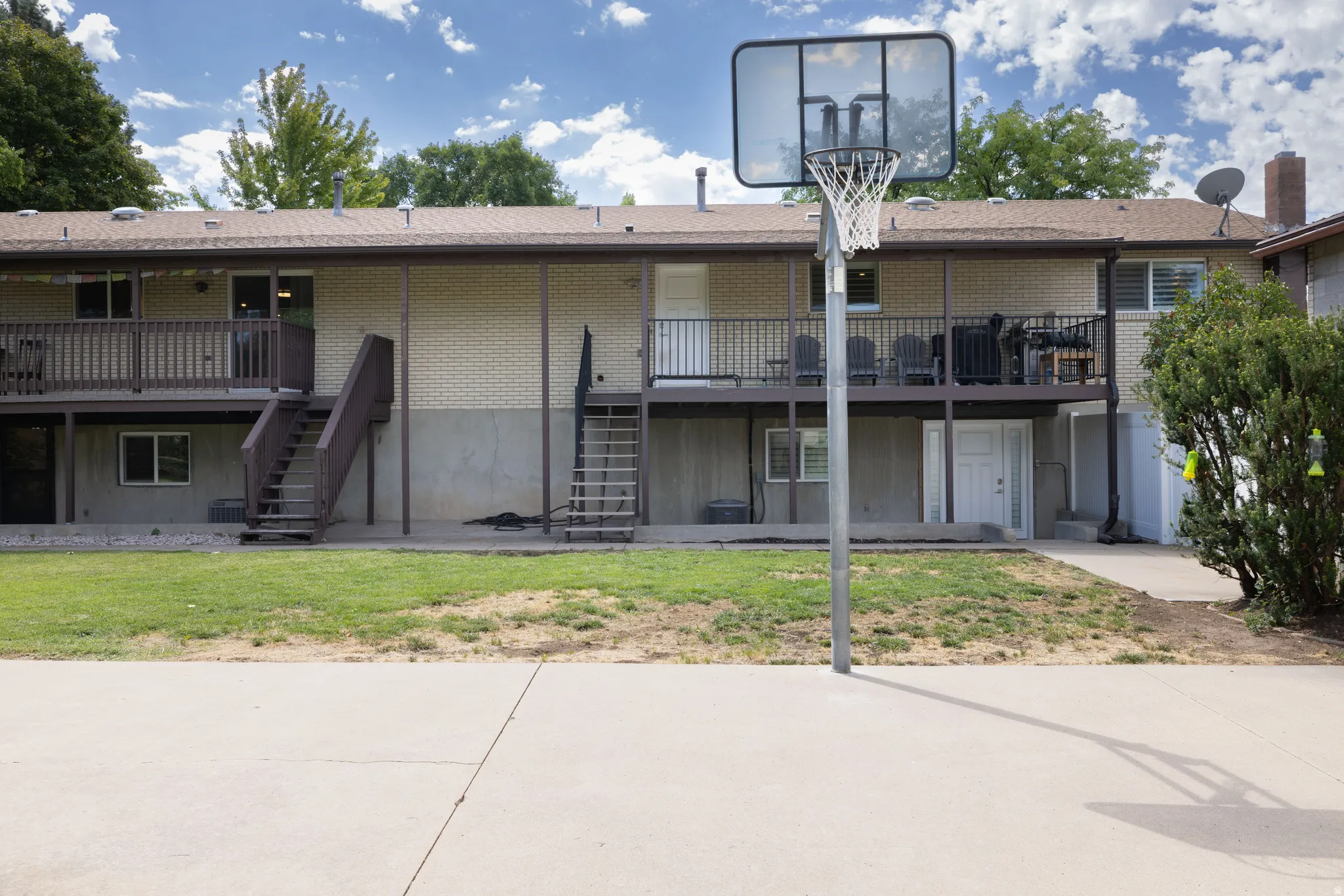 Expansive concrete pad, full-size basketball hoop, and a two-story exterior with an upper-level balcony