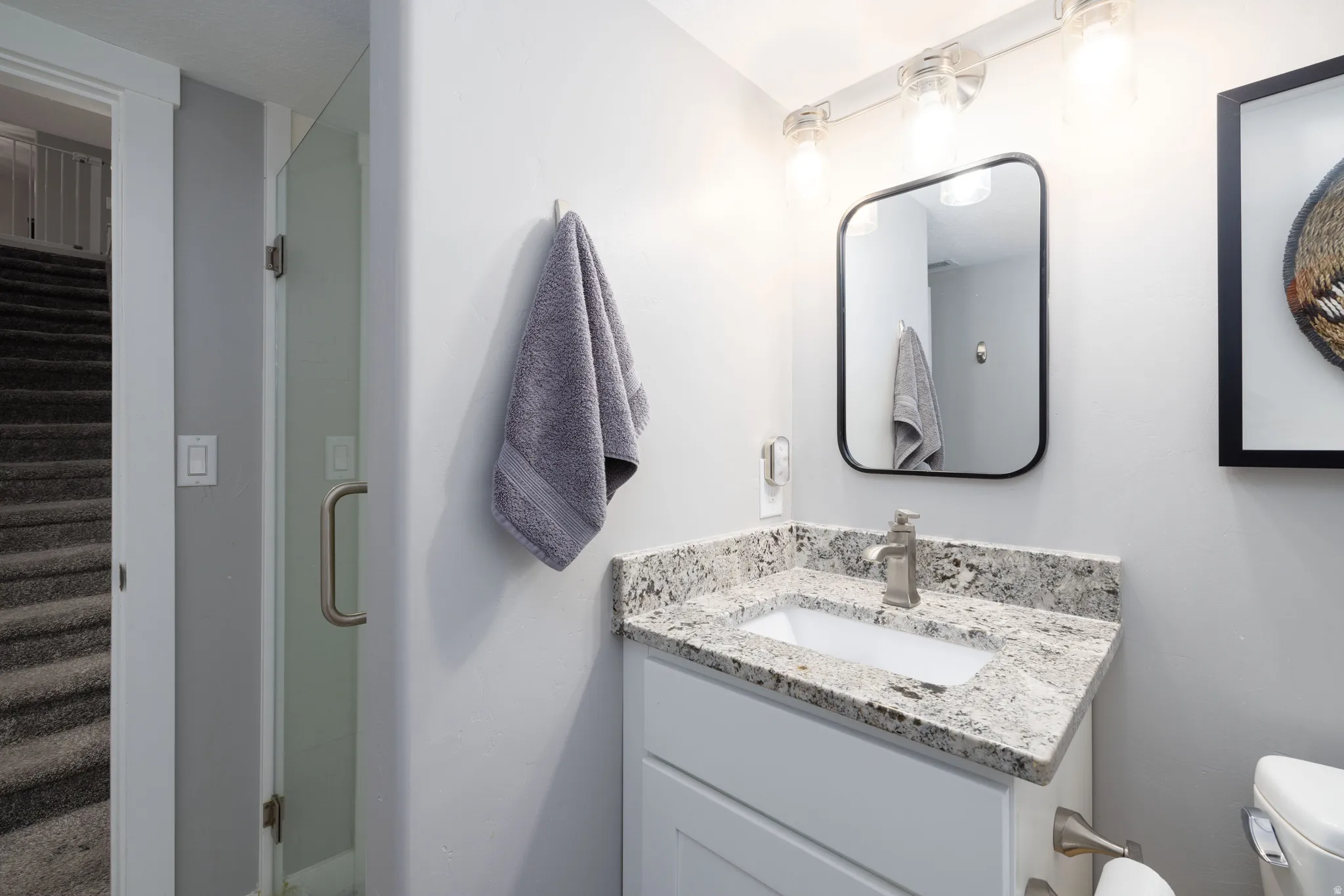 White vanity with a rectangular undermount sink, speckled countertop, and brushed nickel faucet