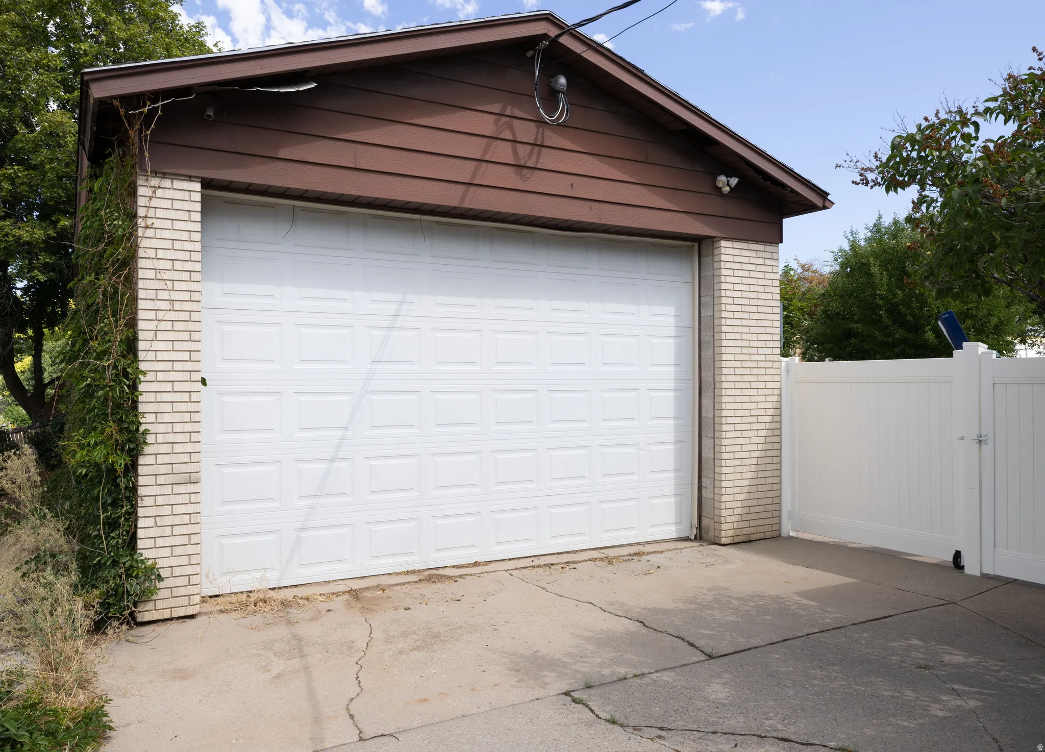 Detached garage featuring brick siding, a white panel garage door, and a brown wood-finish gable