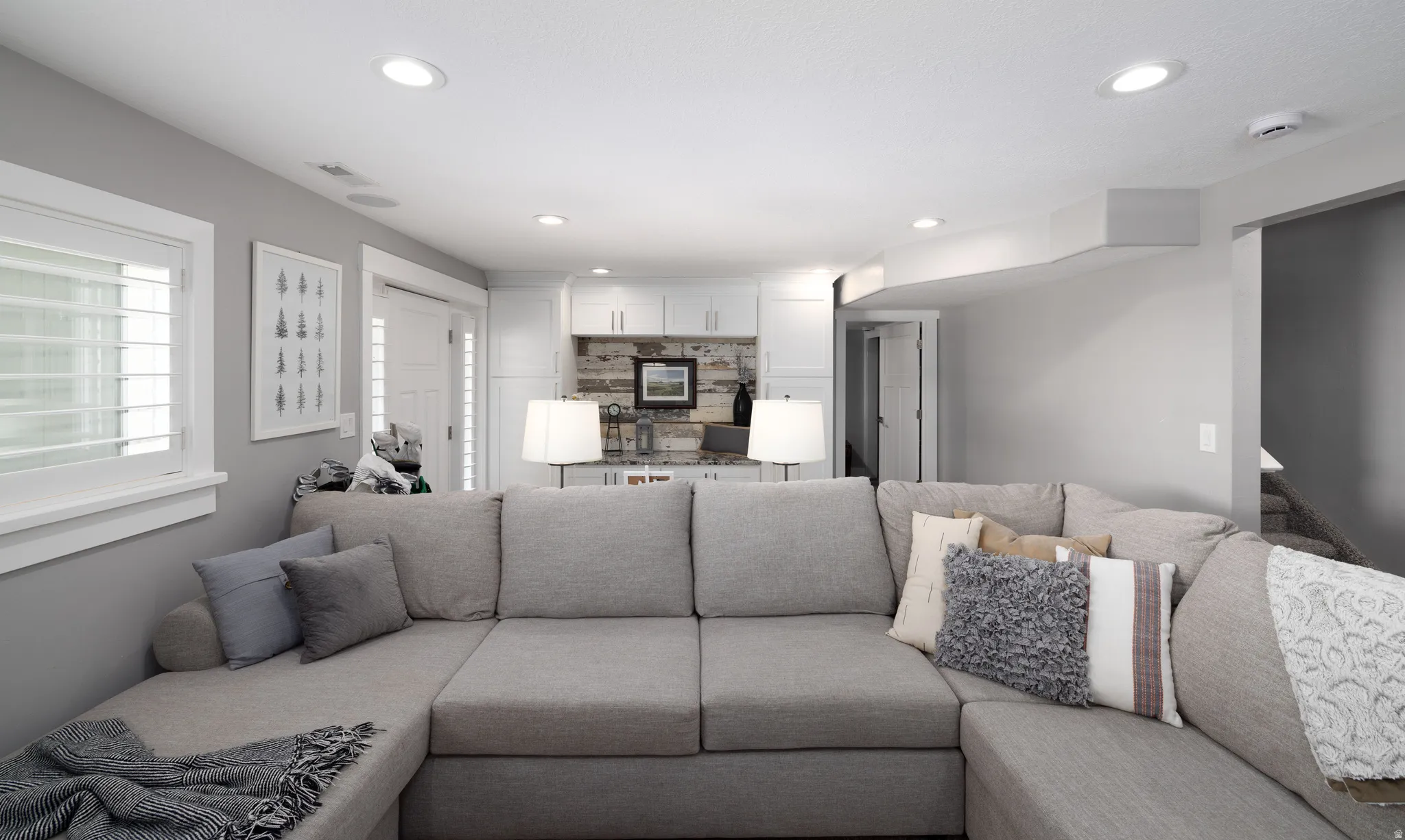 Recessed ceiling lighting, built-in cabinetry, wood-finish backsplash, and window with interior shutters