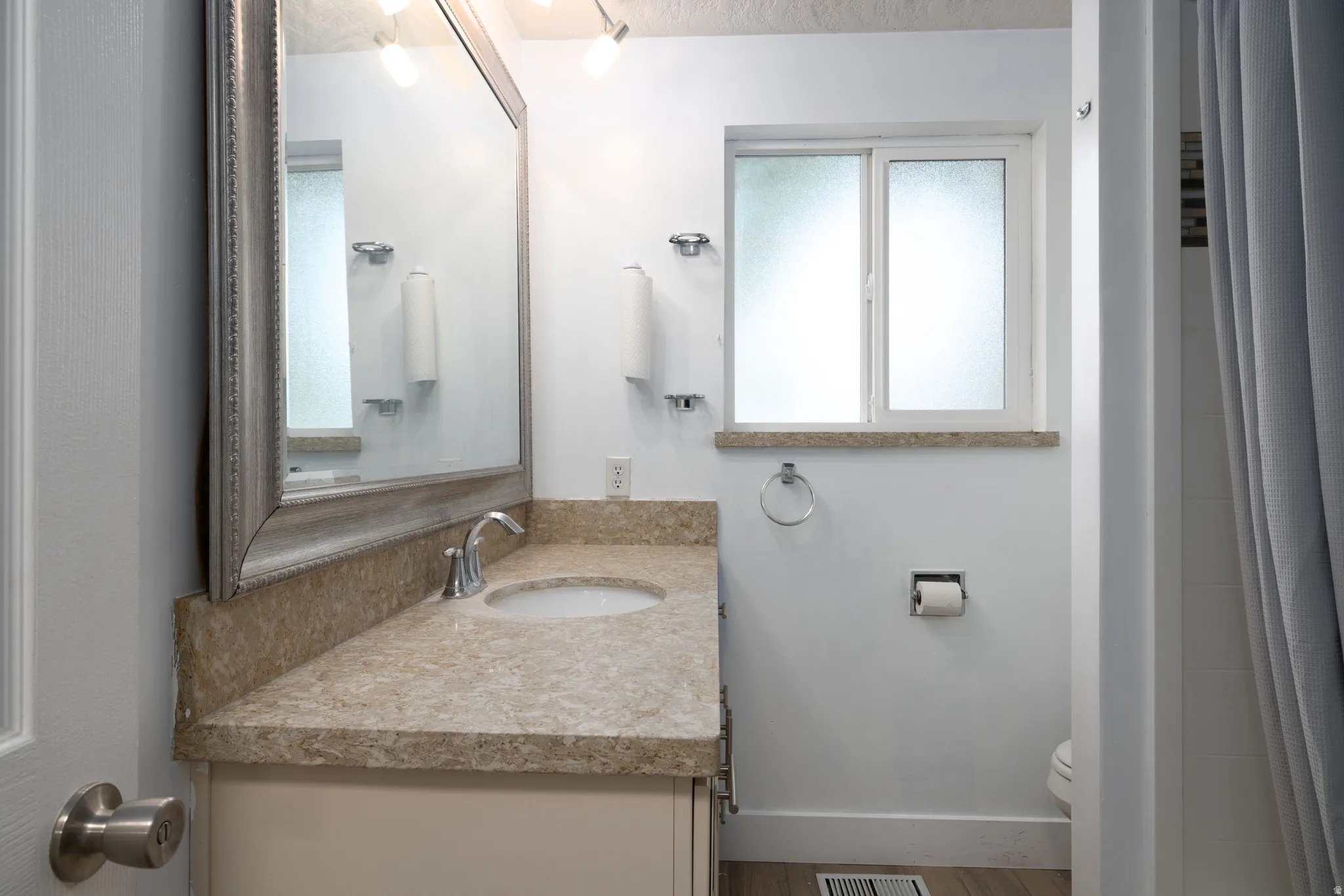 Vanity with a polished chrome faucet, under-mount sink, and stone countertop